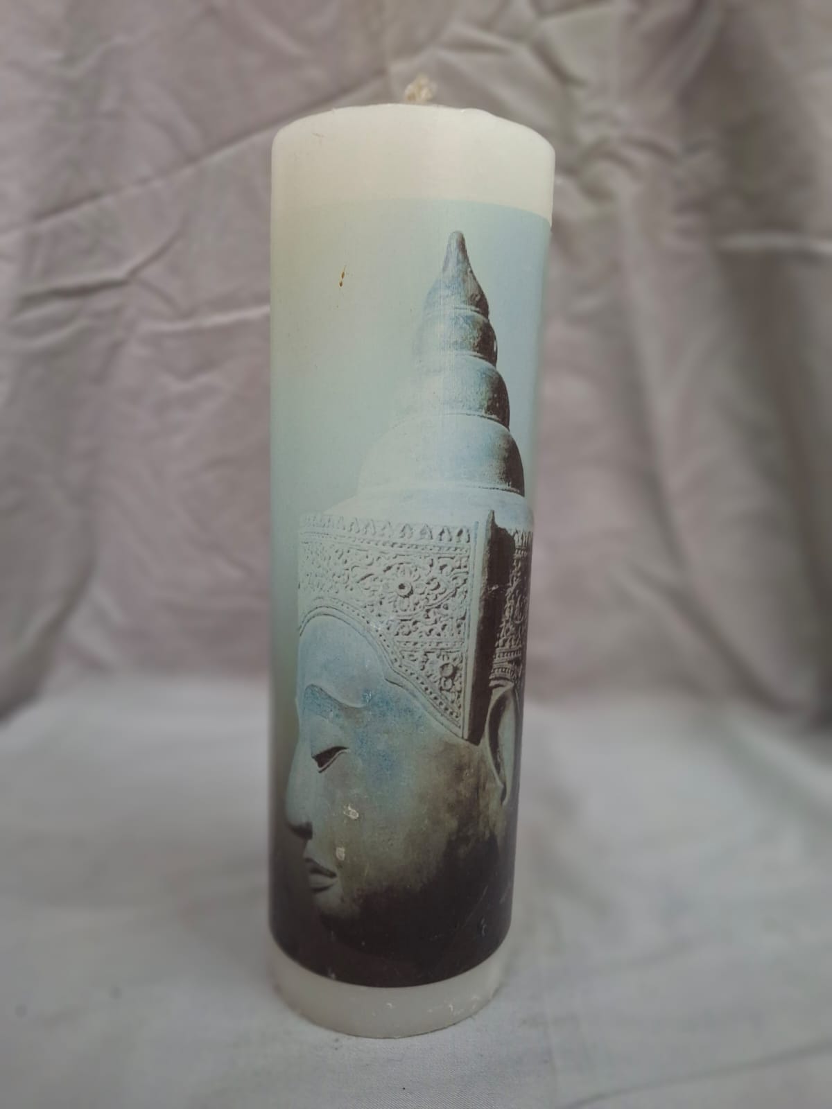 White decorative candle with blue side-view Buddha design