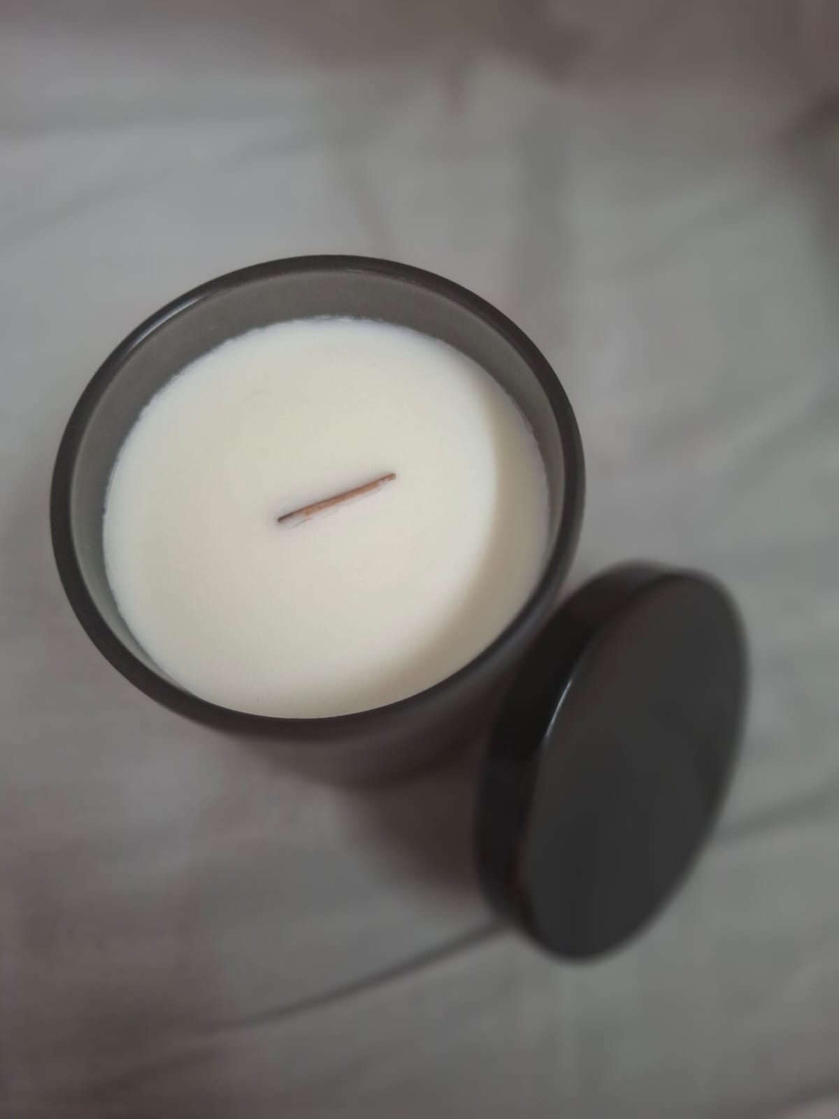 White scented candle in sleek black jar for relaxation and home décor